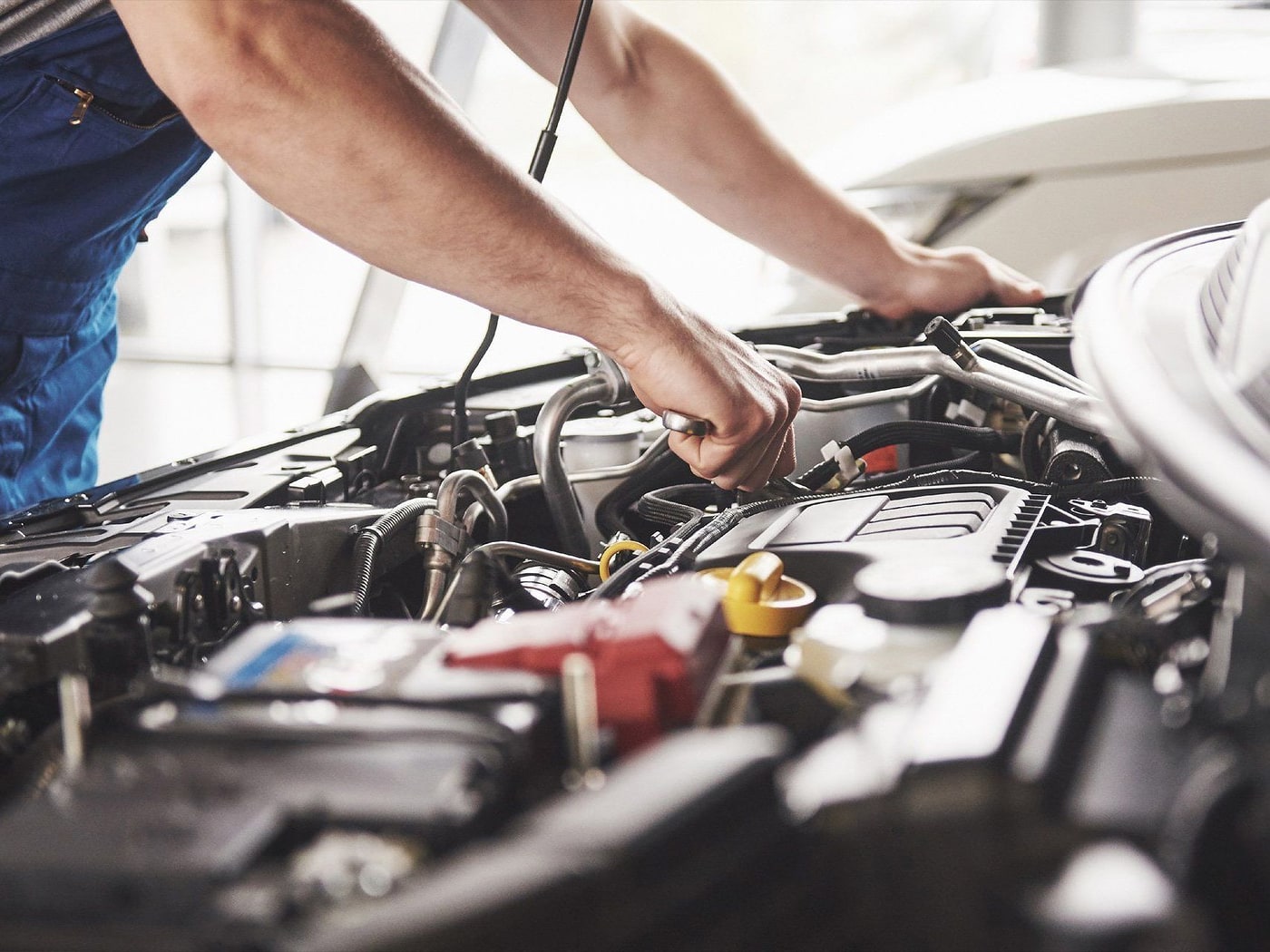 Un tecnico al lavoro nel vano motore di un'auto in officina.